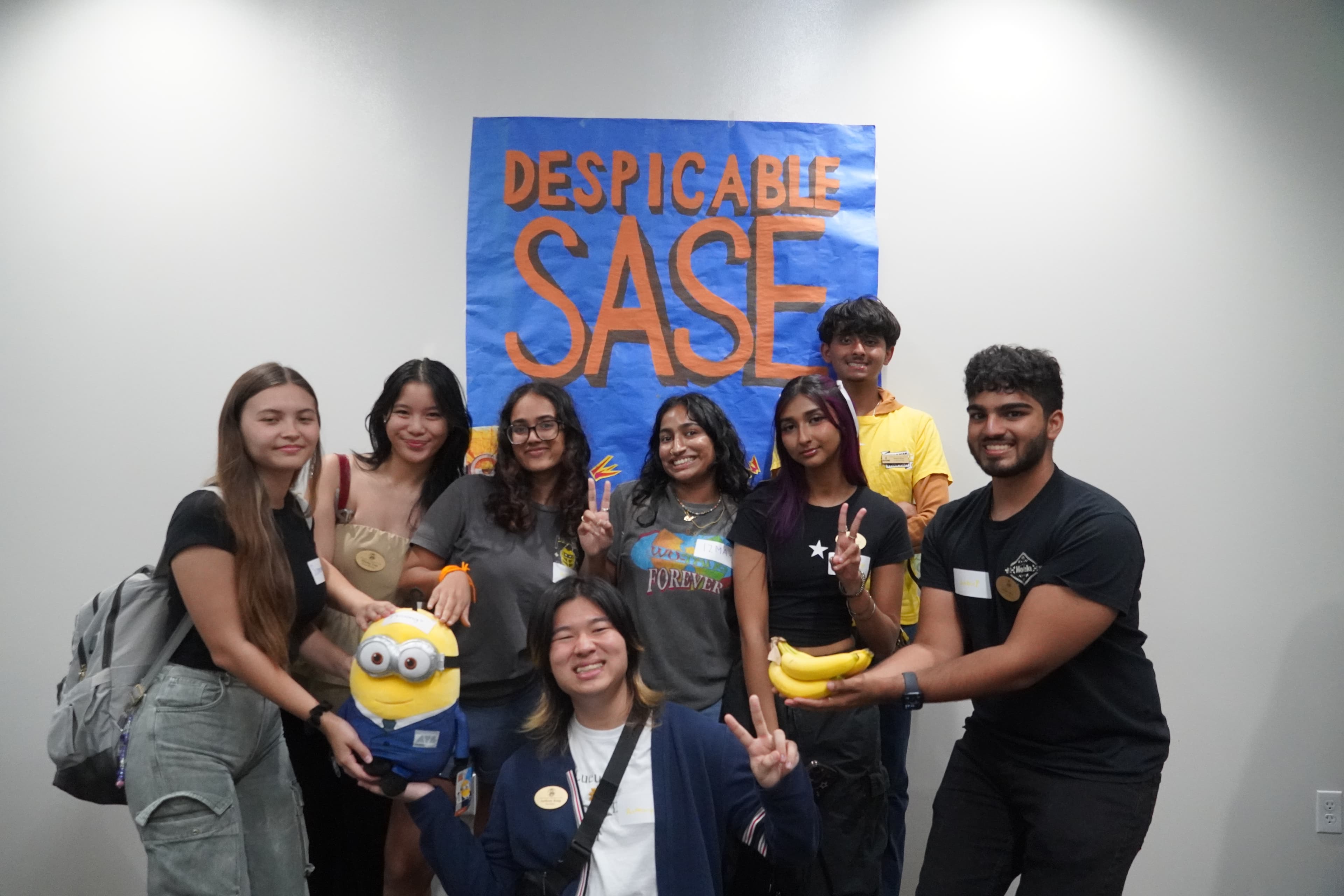 UCF SASE members posing together in front of their handmade Despicable SASE banner
